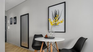 Et moderne spiseområde med et rundt bord, to sorte stole og et indrammet kunstværk på væggen.