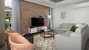 A modern living room with a brick wall, a flat-screen TV, a sofa, and a coffee table. - Trendy Signature Apartment l Wifi l Balcony (Cape Town)