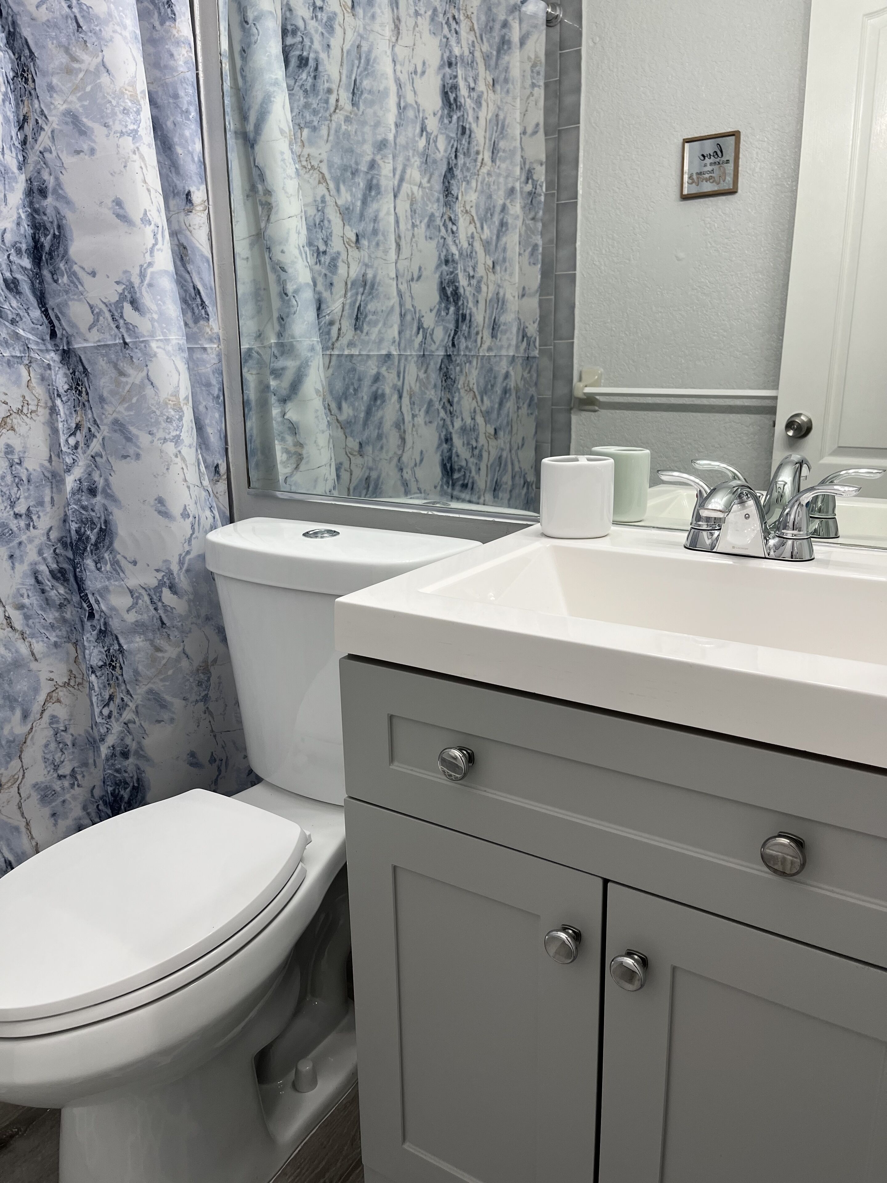 Een badkamer met toilet, wastafel en douchegordijn.