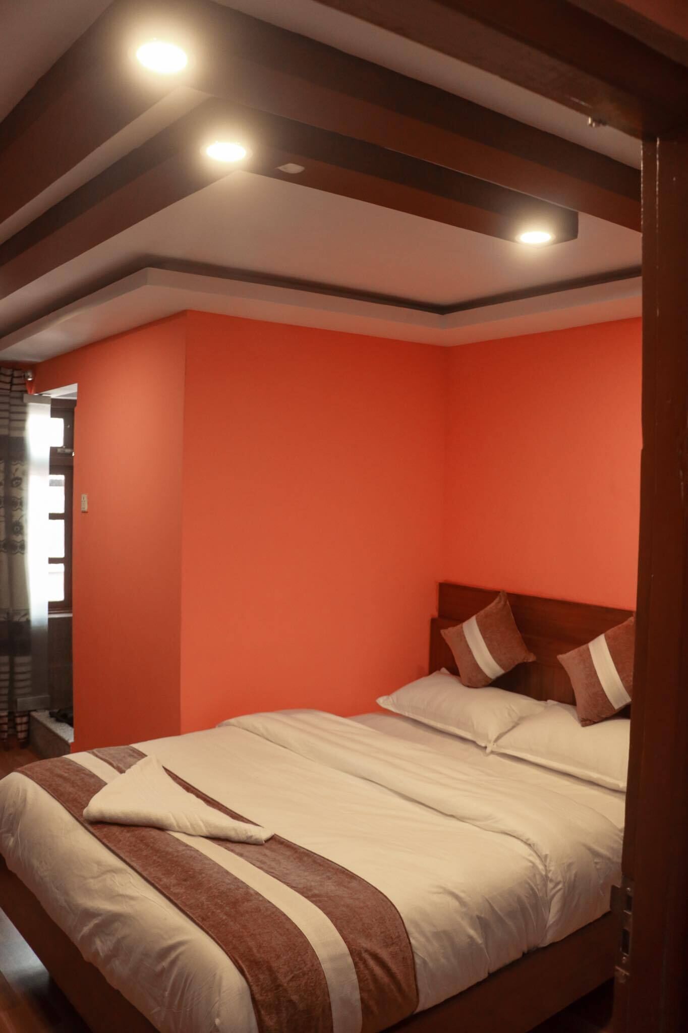 Ein Schlafzimmer mit Bett, Holz-Kopfteil und roter Wand.