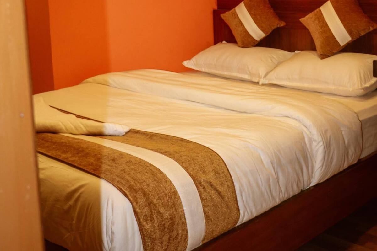 A single bed with a wooden headboard, white bedding, and brown decorative pillows.