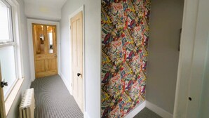 A hallway with a patterned wallpaper, a radiator, and a door leading to another room. - Trendy quirky ground floor Victorian garden flat (Worthing)