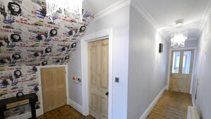 A hallway with wooden flooring, white walls, and a door with a light switch. - Trendy quirky ground floor Victorian garden flat (Worthing)