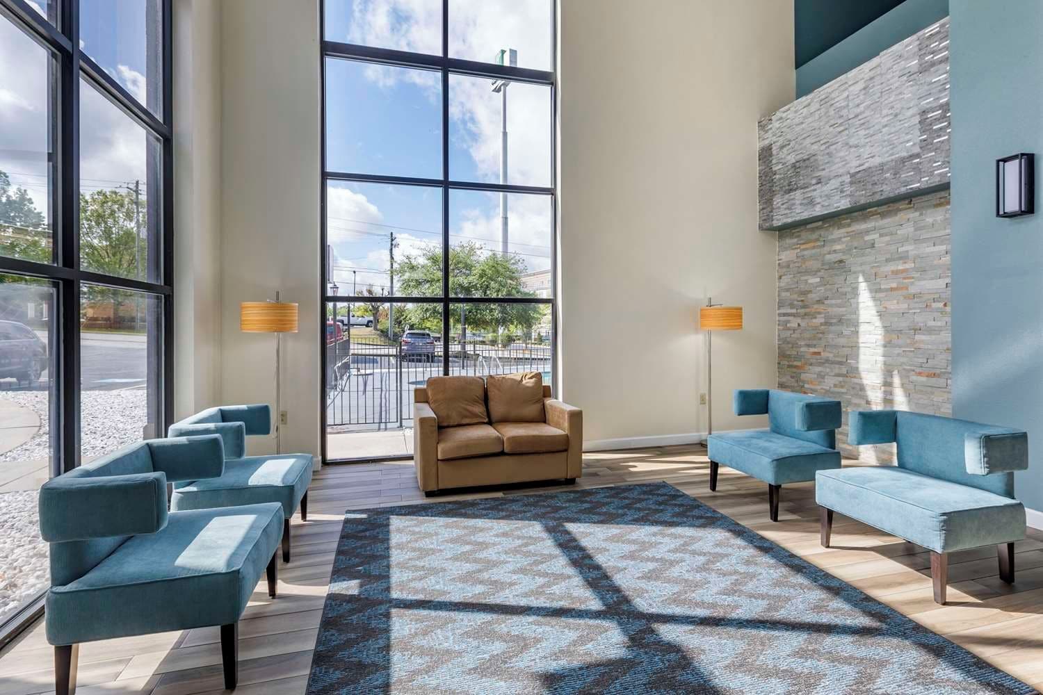 A modern lobby with a large window, a beige sofa, and blue armchairs.