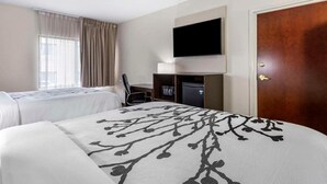 A hotel room with two beds, a TV mounted on the wall, a desk with a chair, and a door. - Sleep Inn & Suites Grovetown - Augusta West (Grovetown)