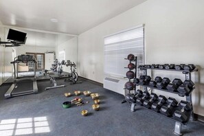 A gym with treadmills, stationary bikes, and a rack of dumbbells.