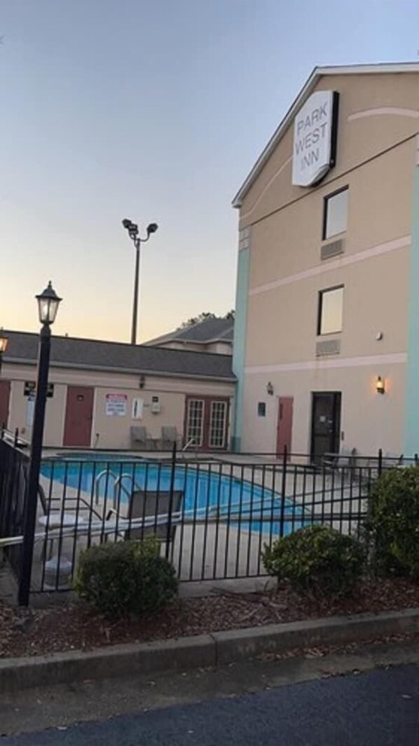 A hotel with a sign reading "Park West Inn" and a swimming pool area enclosed by a fence. - Sleep Inn & Suites Grovetown - Augusta West (Grovetown)