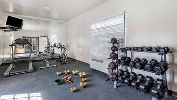 A gym with treadmills, stationary bikes, and a rack of dumbbells.