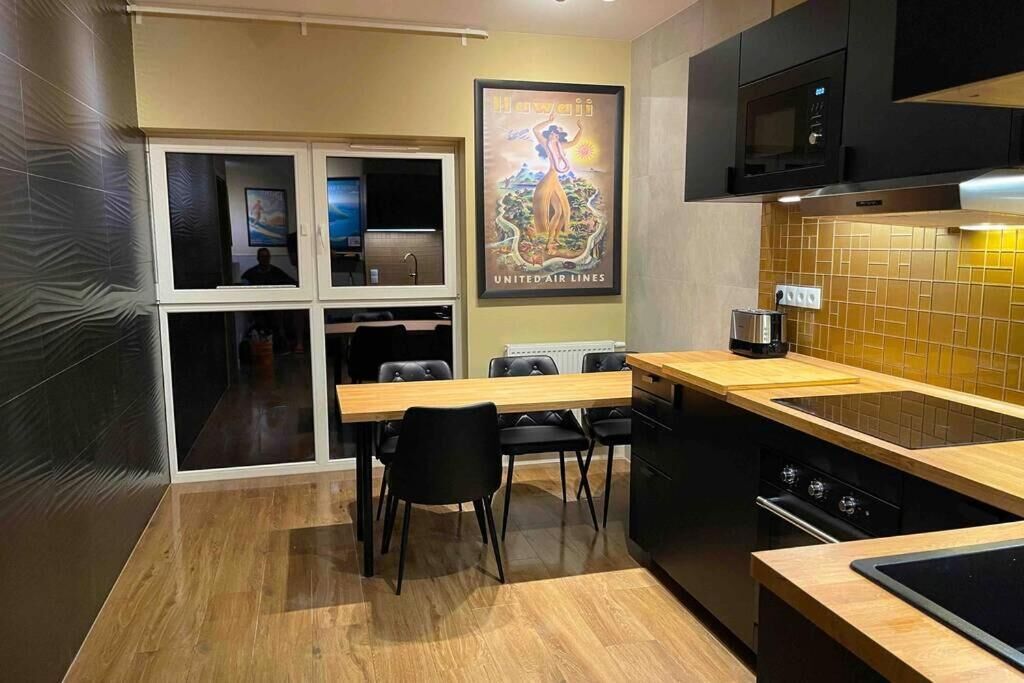 A compact kitchen with a dining area, a microwave, a coffee maker, and a poster on the wall.
