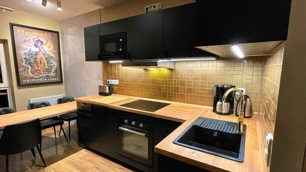 Una cocina moderna con armarios negros, un microondas, una estufa y un lavamanos.