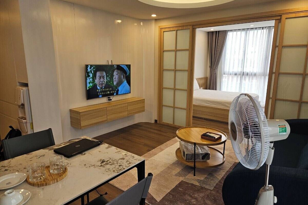 Une chambre d’hôtel moderne équipée d’une télévision, d’un coin repas, d’un canapé et d’un ventilateur.