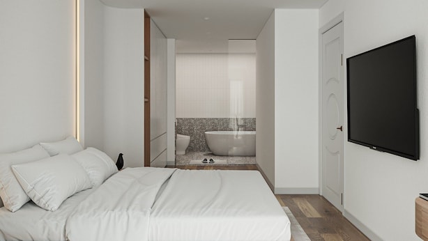 A modern bedroom with a large bed, a built-in desk, a TV, and a bathroom with a bathtub.