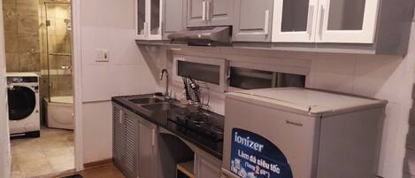 A compact kitchen with grey cabinets, a built-in microwave, and a refrigerator with a Panasonic Ionizer.