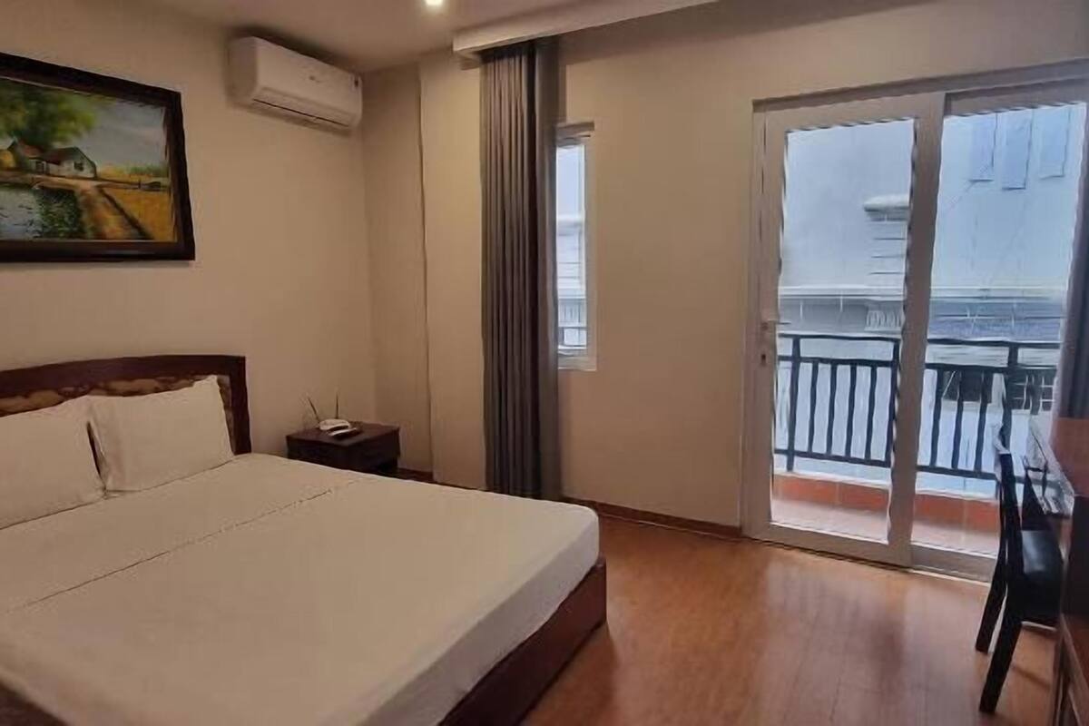 Une chambre d’hôtel avec un lit, un bureau, une chaise, une télévision, un tableau et un balcon avec vue.