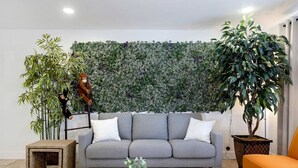 A living room with a grey sofa, a coffee table, a small side table, and a large green wall with plants. - Weber · Jungle House, minutes away from ASU/ Old Town (Tempe)