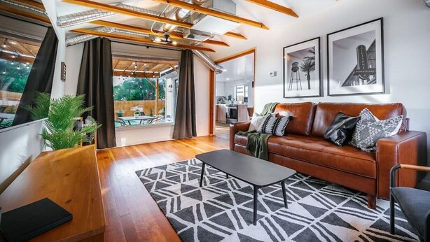 Un salon spacieux avec un plafond en bois, un canapé en cuir et un tapis à motifs.