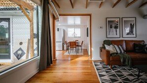 Un salon moderne avec un plancher en bois, un canapé en cuir marron et un coin repas comprenant une table et des chaises.