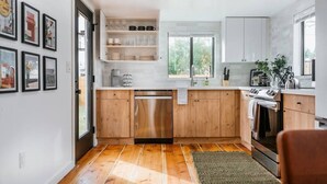 Une cuisine moderne avec des meubles en bois, un lave-vaisselle en acier inoxydable et une fenêtre qui laisse entrer la lumière naturelle.