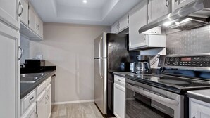 Una cocina moderna con electrodomésticos de acero inoxidable, horno empotrado y cafetera.
