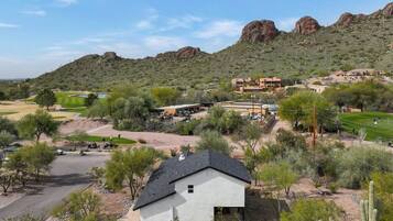 A residential area with houses, a golf course, and a mountainous backdrop.