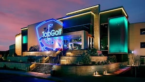 En moderne bygning med et tydeligt, oplyst skilt, der viser "TopGolf".