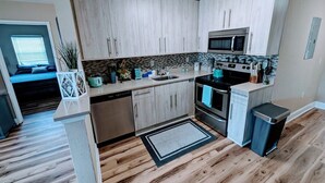 A modern kitchen with light wood cabinets, a stainless steel microwave, and a dishwasher.