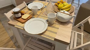 A dining table set with plates, a teapot, a pitcher, a cup, a jar of jam, bread, and fruit. - Piccola casetta, appena ristrutturata, un vero gioiellino, tra le vie del borgo. (Castellammare del Golfo)