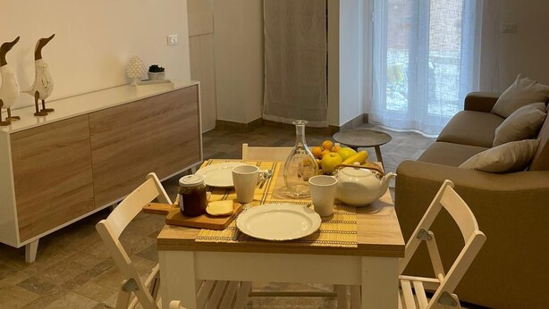 A modern living space with a dining area, a sofa, and a TV mounted on the wall. - Piccola casetta, appena ristrutturata, un vero gioiellino, tra le vie del borgo. (Castellammare del Golfo)