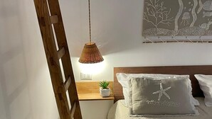 A bedroom with a wooden ladder, a bedside table with a plant, and a wall-mounted artwork. - Piccola casetta, appena ristrutturata, un vero gioiellino, tra le vie del borgo. (Castellammare del Golfo)