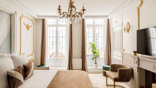 Ein Hotelzimmer mit einem großen Bett, einer Sitzecke, einem Fernseher und Blick auf die Stadt durch große Fenster.