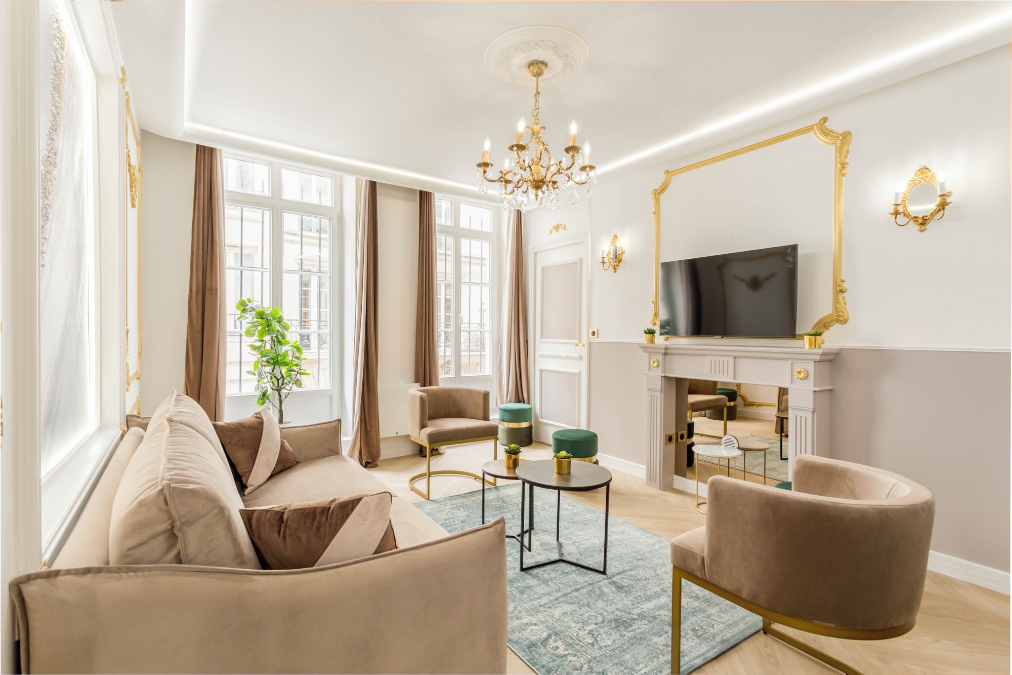 A spacious living room with a beige sofa, a round coffee table, and a TV mounted above a fireplace.
