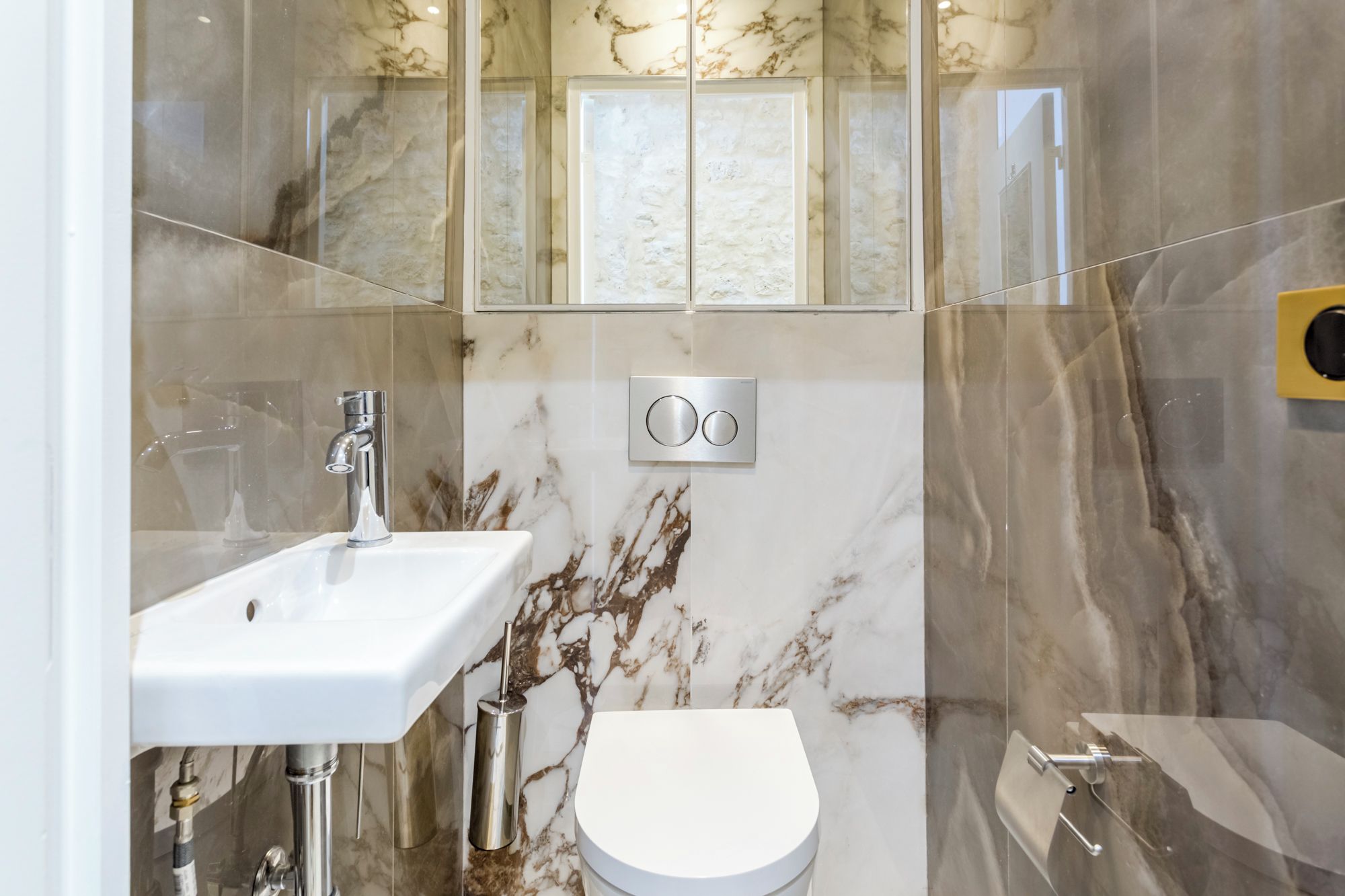 A modern bathroom with a white sink, a toilet, and a shower area.