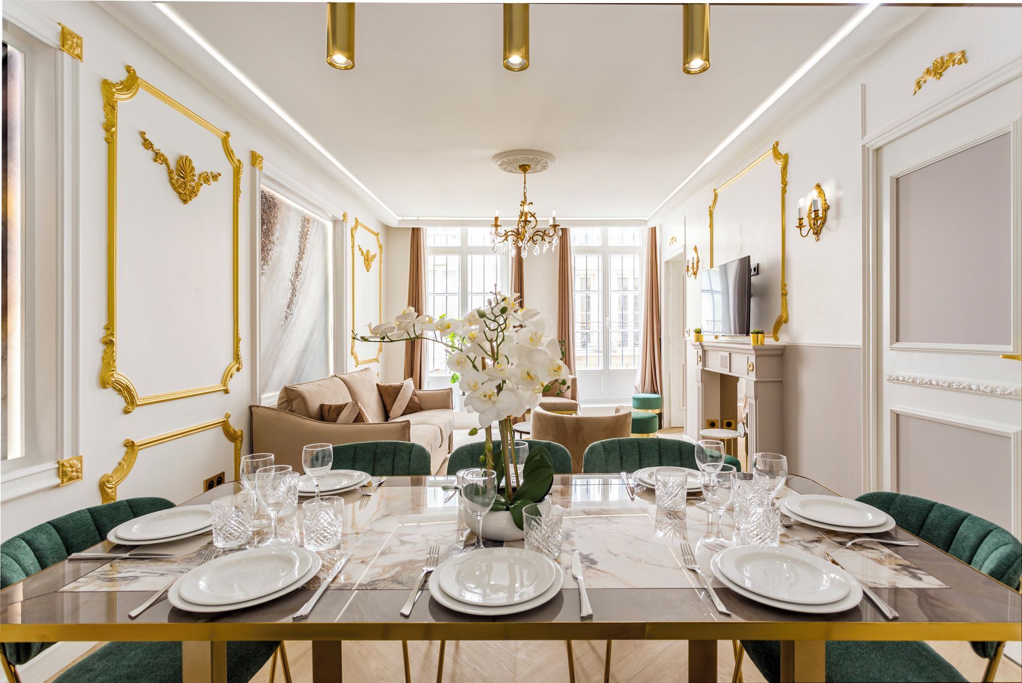 Ein Esszimmer mit einem Marmortisch, gedeckt für sechs Personen, goldenen Akzenten an den Wänden und einem Kronleuchter.