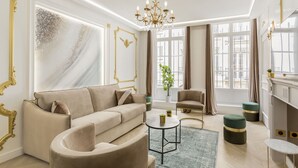 Ein modernes Wohnzimmer mit einem beigen Sofa, einem runden Couchtisch und einer Kristallleuchtre.