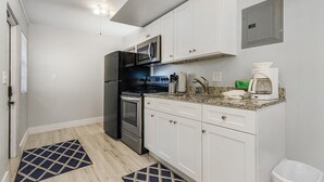 A modern kitchen with white cabinets, stainless steel appliances, and a granite countertop. - 2-Bedroom Condo with screened patio - Manatee - Welcome to our newly renovated, spacious and luxurious two-bedroom condo! (Matlacha)