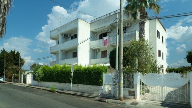 A two-story residential building with balconies, a gated entrance, and a palm tree. - Vacation Apartment Samari Three (Gallipoli)