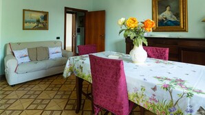 A dining area with a table set for four, surrounded by chairs, a sofa, and a cabinet. - Vacation Apartment Samari Three (Gallipoli)