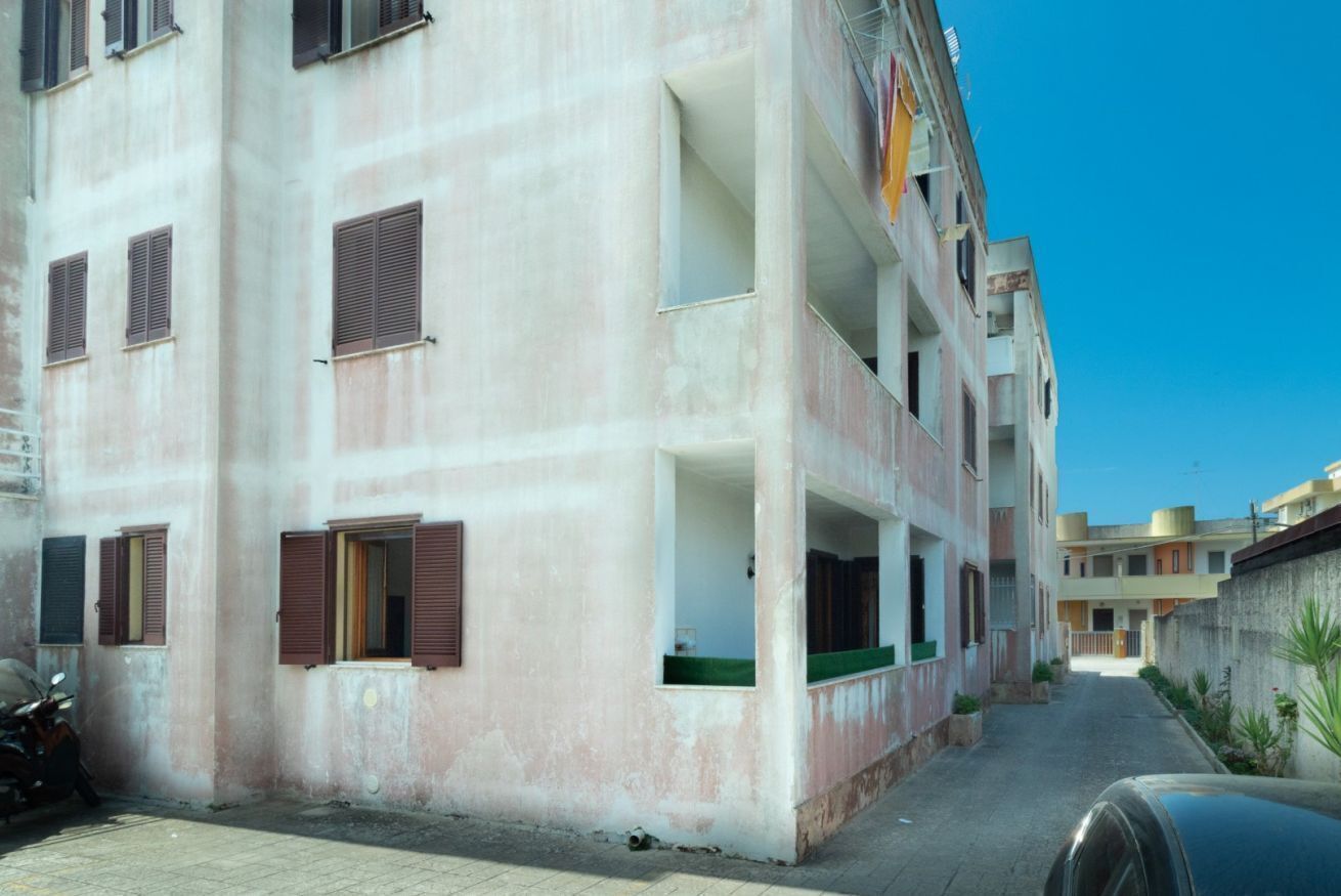 Um edifício de vários andares com varandas e uma rua estreita.