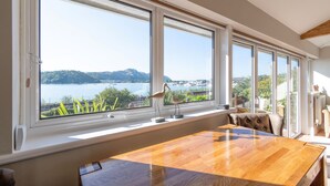 Um quarto com uma grande janela com vista para um lago, uma mesa de madeira e uma cadeira.