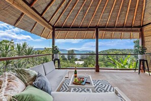 A balcony with a view of the sea, a sofa, a table with a bottle and glasses, and potted plants. - Idyllic Whitsunday Holiday Home with amazing views (Mandalay)