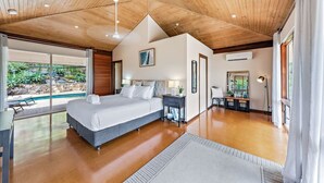 Ein geräumiges Schlafzimmer mit einem großen Bett, einem Schreibtisch und Blick auf einen Swimmingpool.