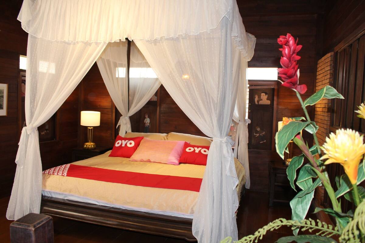 Ein Bett mit Baldachin, ein Nachttisch mit Lampe und eine Blumenkomposition.