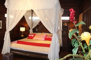 Ein Bett mit Baldachin, ein Nachttisch mit Lampe und eine Blumenkomposition.