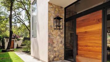 A modern house with a stone facade, a large wooden door, and a well-maintained lawn.