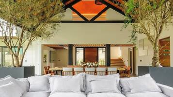 A spacious living area with a large sectional sofa, a dining area with a table and chairs, and a high ceiling with exposed beams.