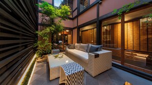 A cozy outdoor seating area with a cushioned bench, a low table, and a sofa with cushions.