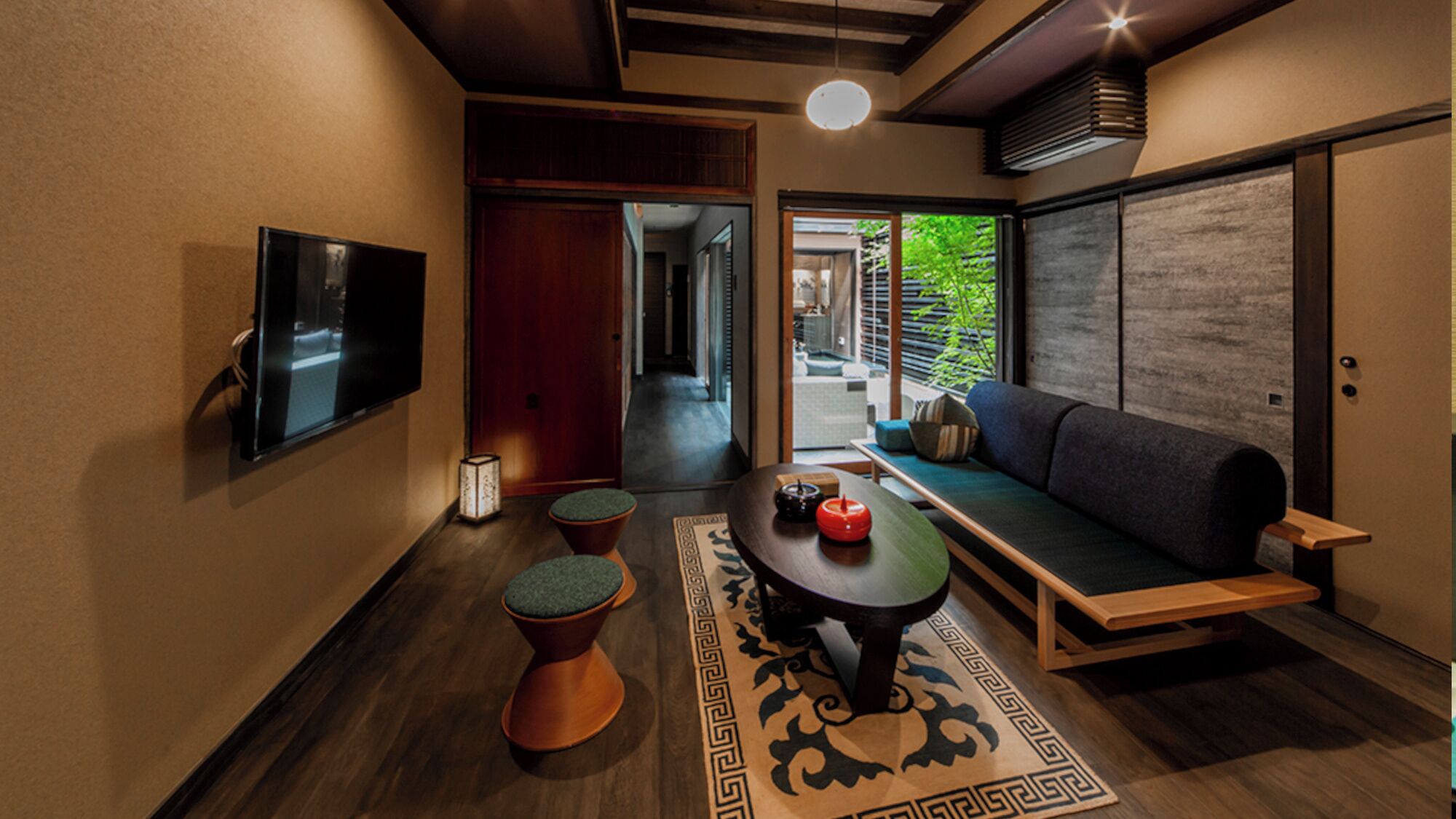 Un intérieur moderne avec un canapé, une table décorée de bougies, un téléviseur et un tapis à motifs.