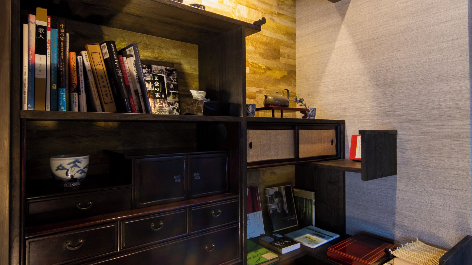 A bookshelf with books and decorative items, a wooden cabinet with drawers, and a small shelf with a bowl and books.