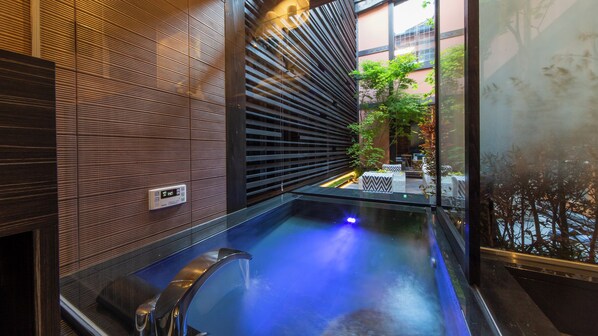 A modern bathroom with a glass-enclosed hot tub, a digital thermostat, and a view of the outdoor seating area. - Sumiya Seica (Takayama)