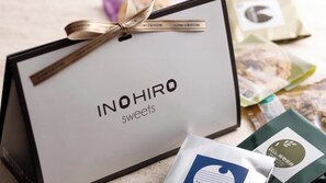 A gift box labeled 'INOHIRO sweets' with a ribbon, and some packaged sweets in the background. - Sumiya Seica (Takayama)